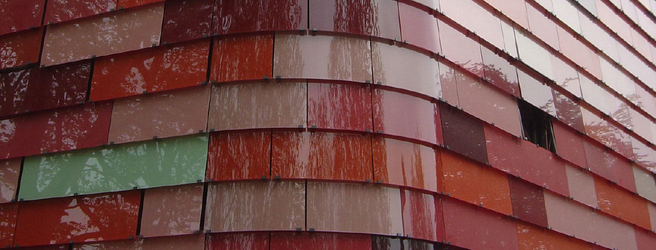 Farblich siebbedruckte Glasschuppenfassade mit Öffnungslamellen